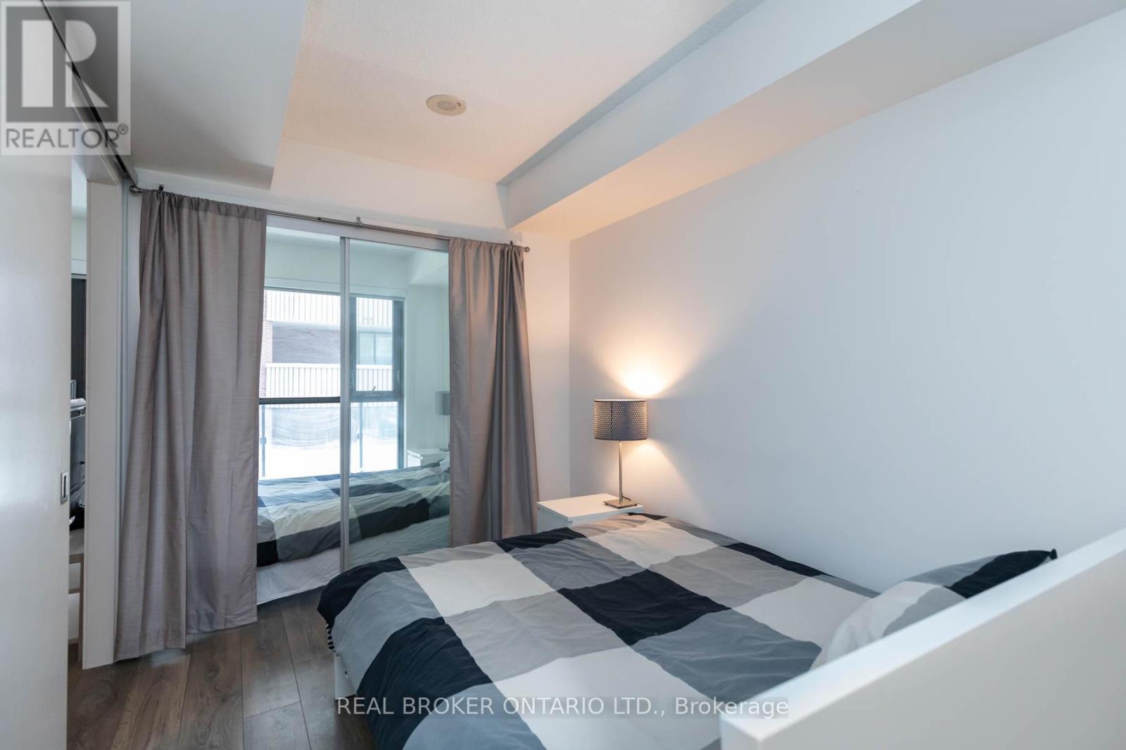 A bedroom with a large bed and a window with curtains.