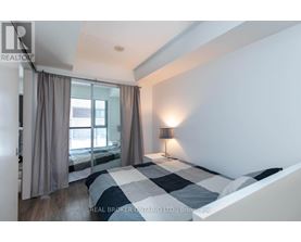 A bedroom with a large bed and a window with curtains.