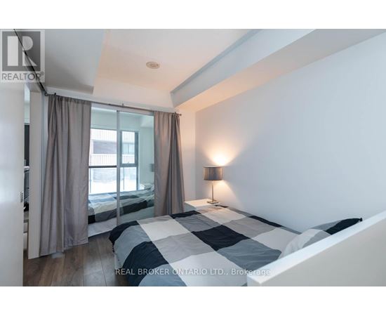 A bedroom with a large bed and a window with curtains.