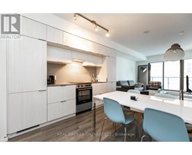 A modern kitchen with white cabinets and a dining table.