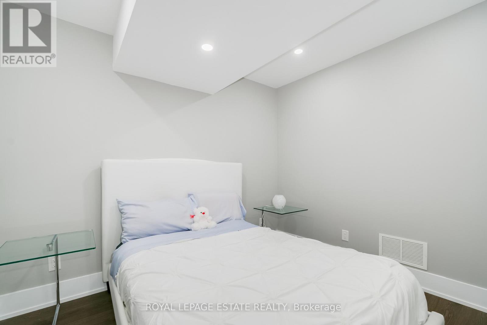 A bedroom with a white bed and a glass end table.