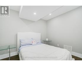 A bedroom with a white bed and a glass end table.