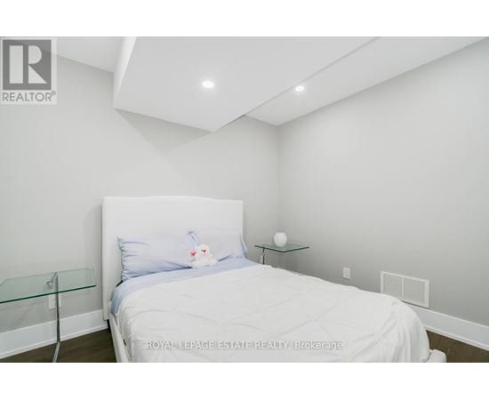 A bedroom with a white bed and a glass end table.