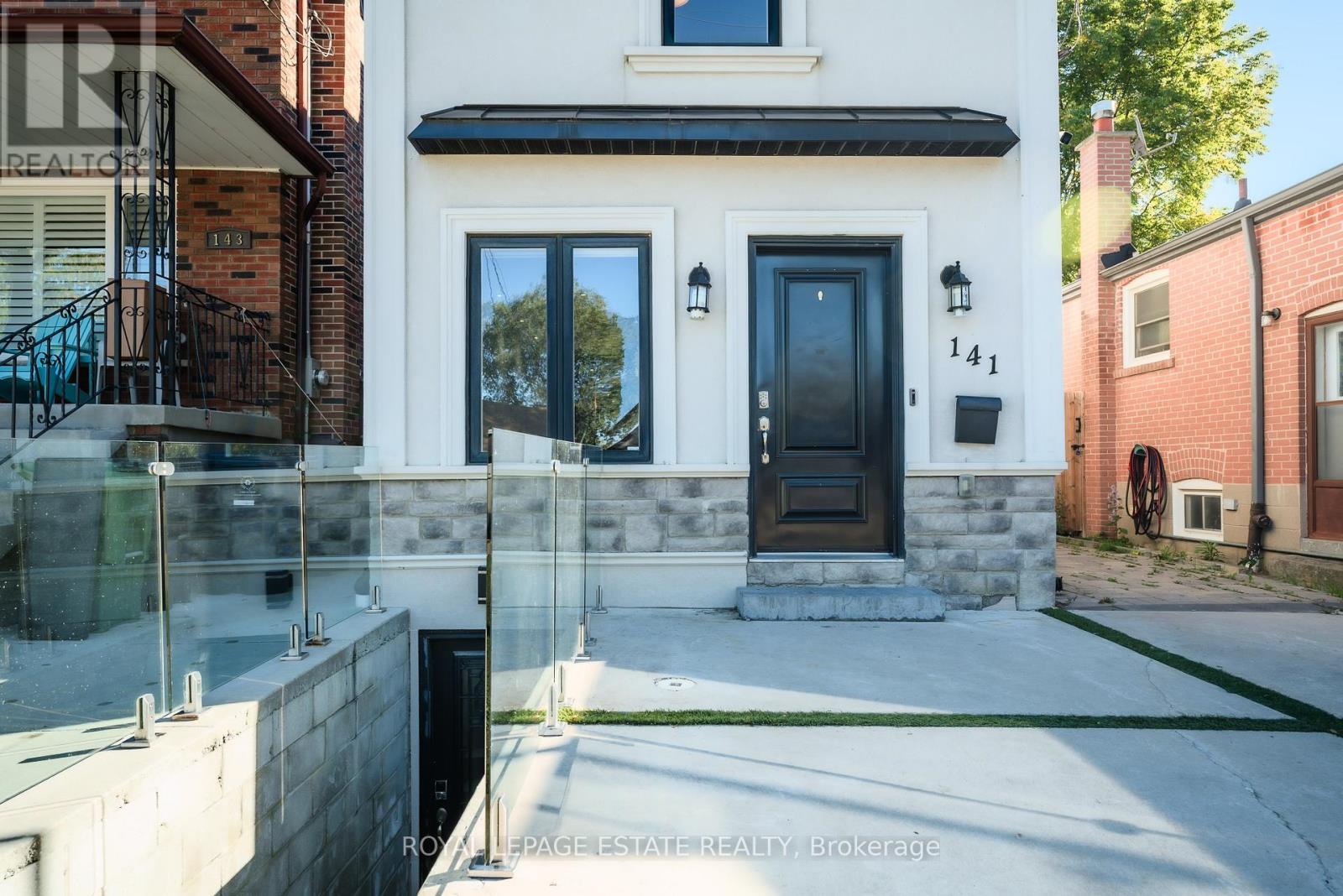 A modern house with a black front door and a glass railing.