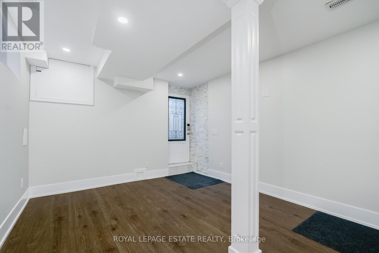 A spacious room with wooden floors and white walls.