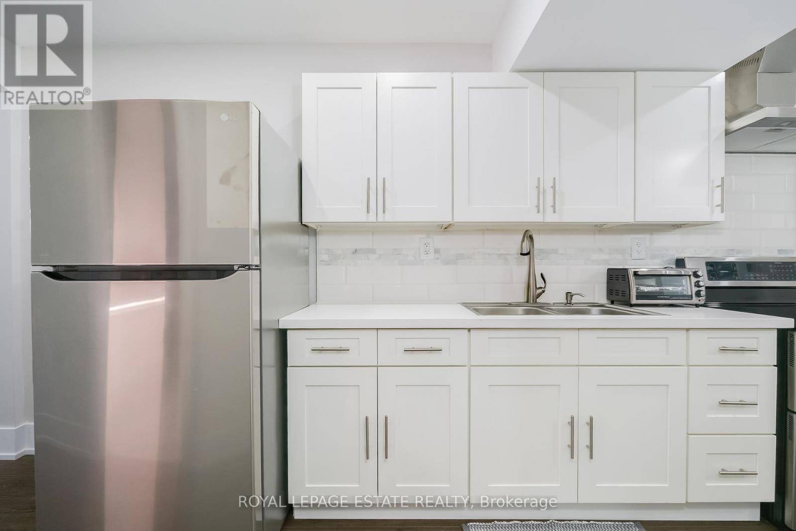 A kitchen with white cabinets and a stainless steel refrigerator.