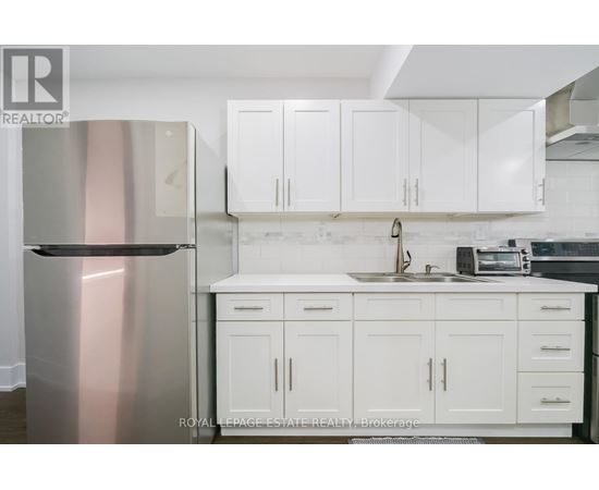 A kitchen with white cabinets and a stainless steel refrigerator.