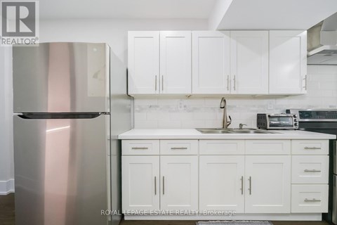 A kitchen with white cabinets and a stainless steel refrigerator.