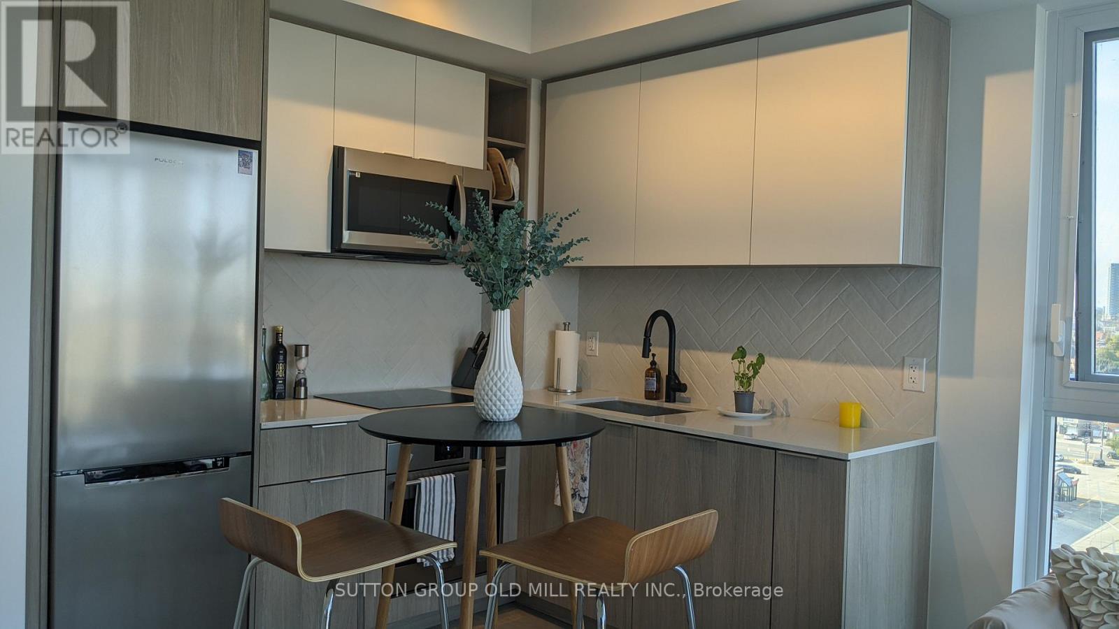 A kitchen with a table and chairs and a refrigerator.