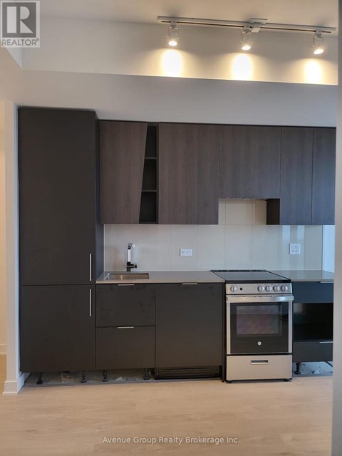 A modern kitchen with dark brown cabinets and a stainless steel oven.