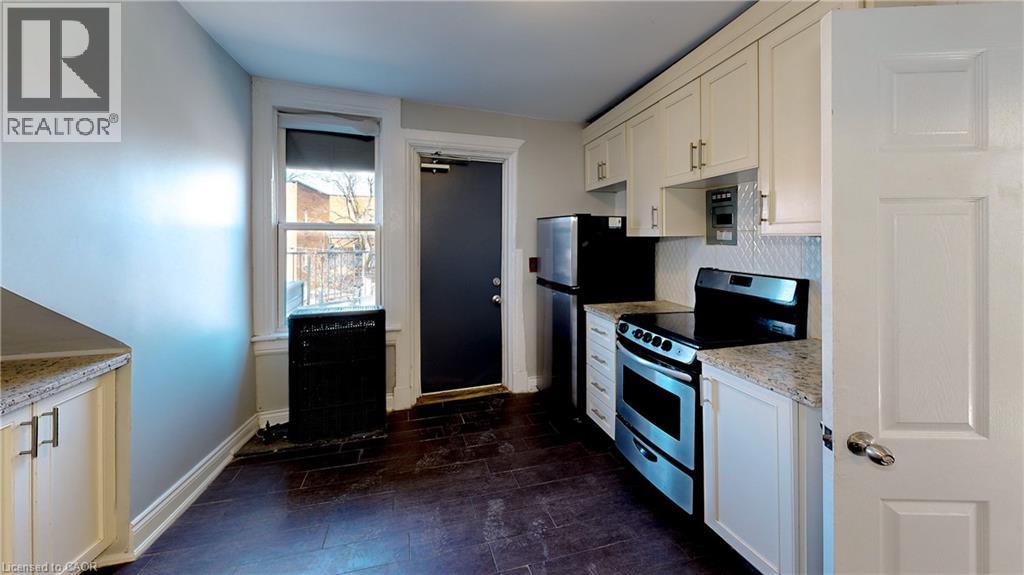 A kitchen with a black refrigerator and stove top oven.