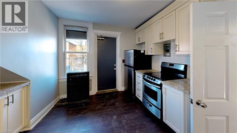A kitchen with a black refrigerator and stove top oven.