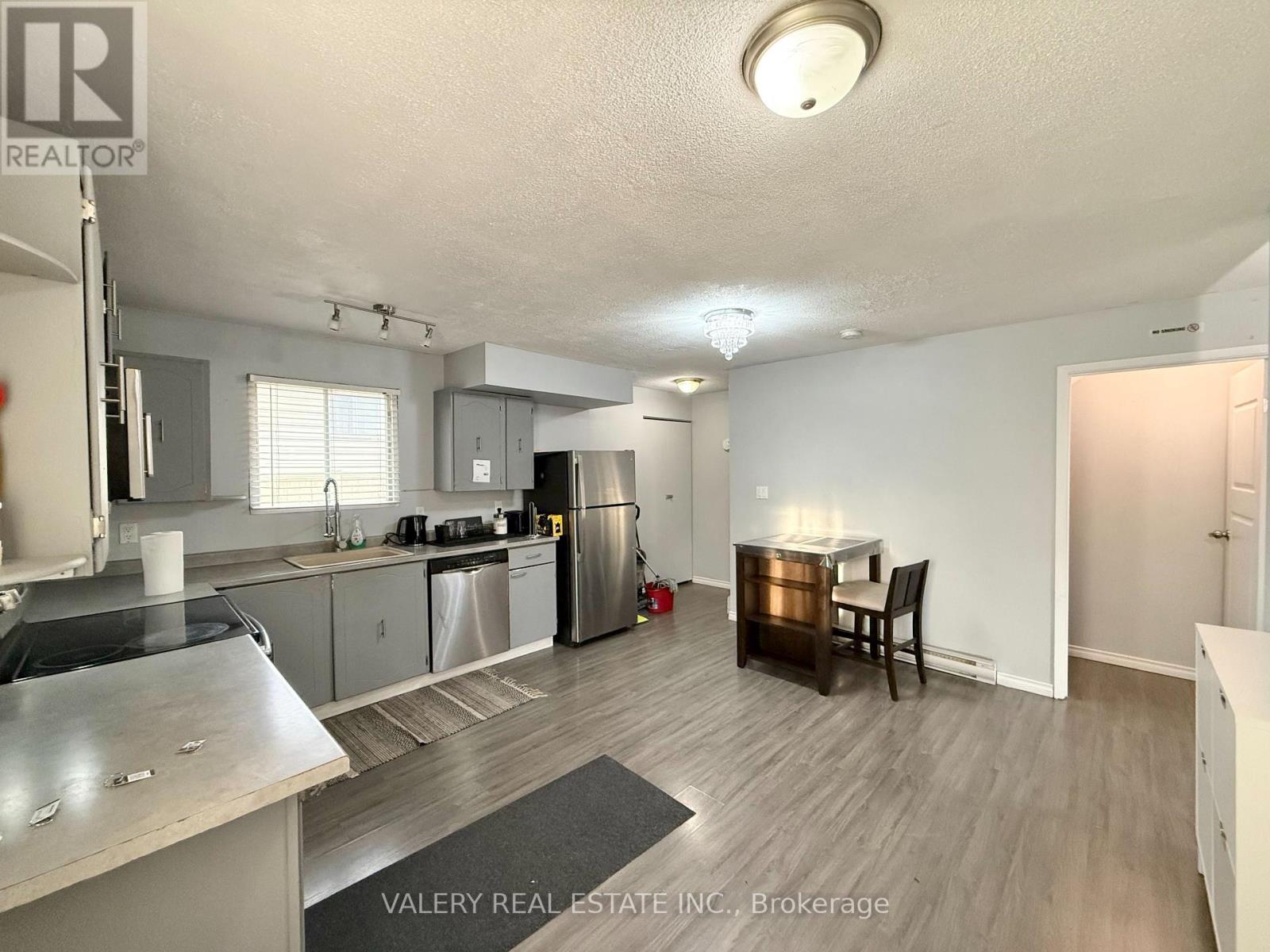 A kitchen with stainless steel appliances and a dining table with chairs.