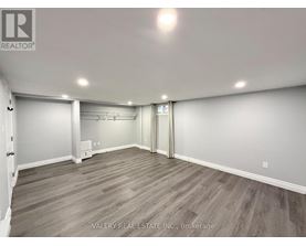 A spacious room with wood flooring and white walls.