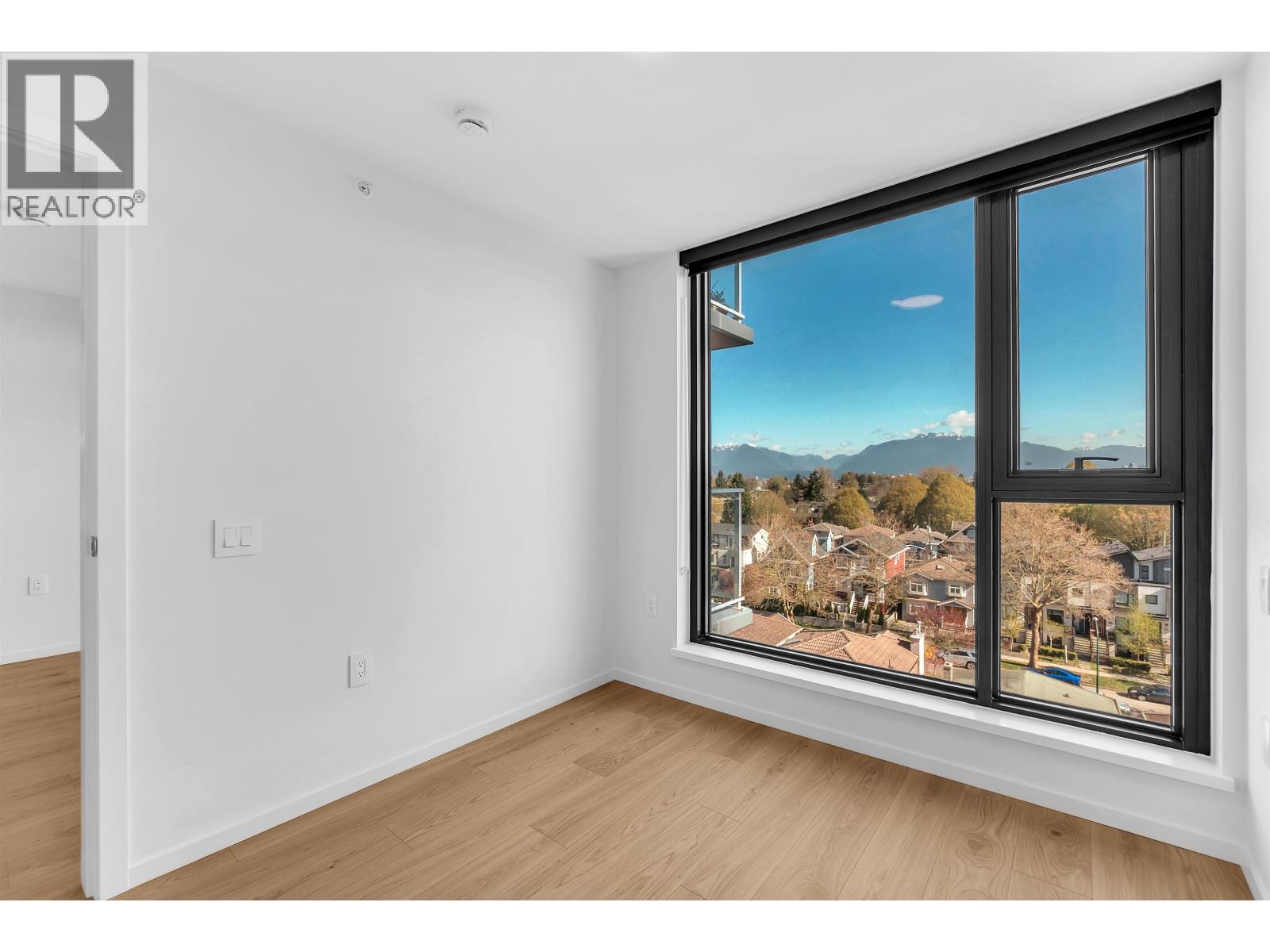 A room with a large window showing a view of houses and trees.