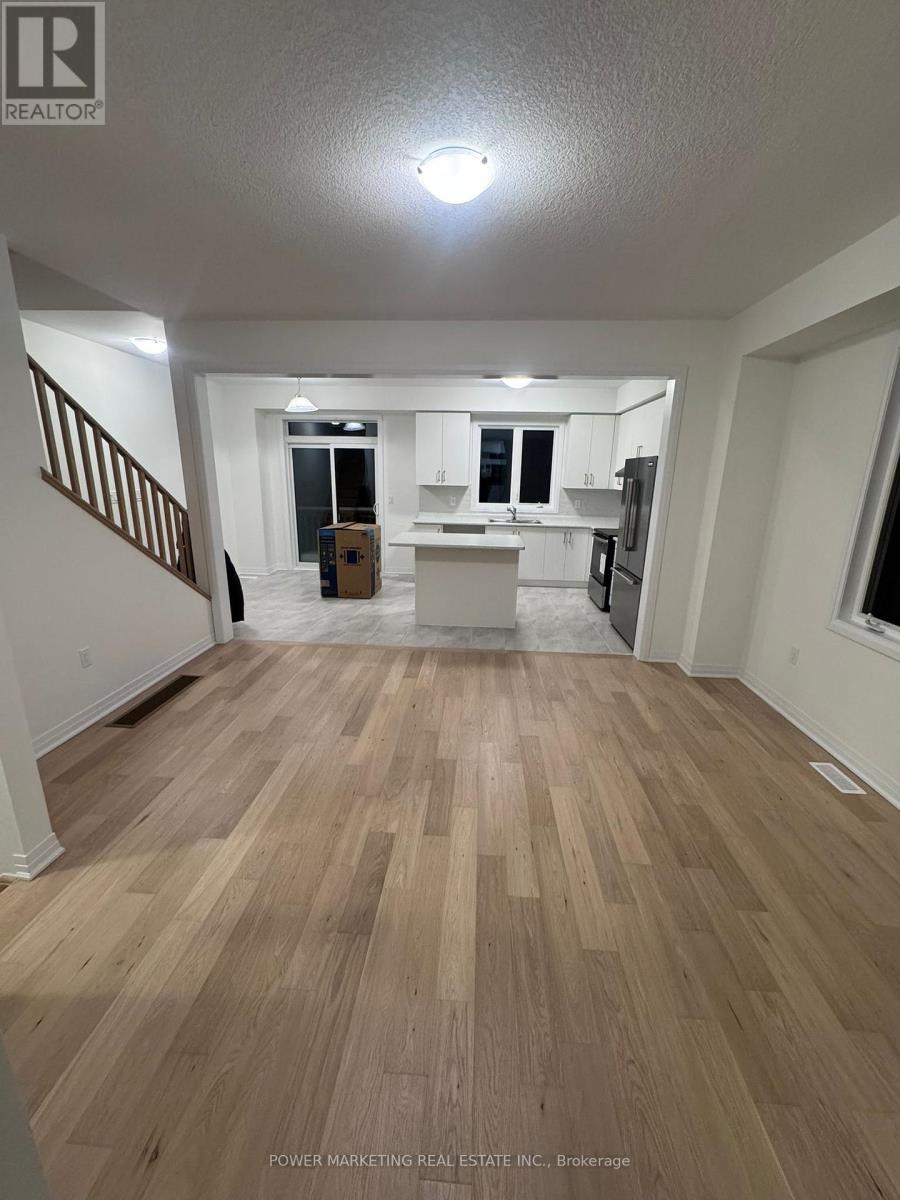 A room with wooden flooring and a staircase on the left side.