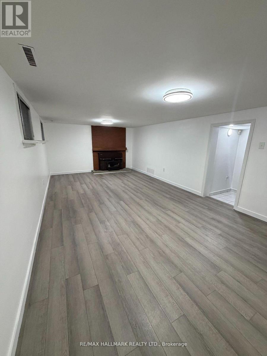A spacious room with a fireplace and wood flooring.