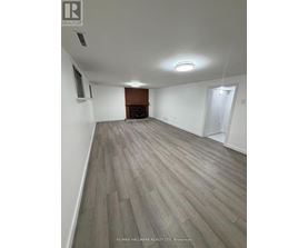 A spacious room with a fireplace and wood flooring.