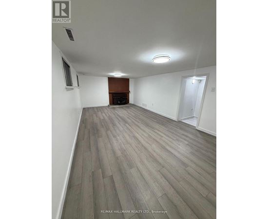 A spacious room with a fireplace and wood flooring.