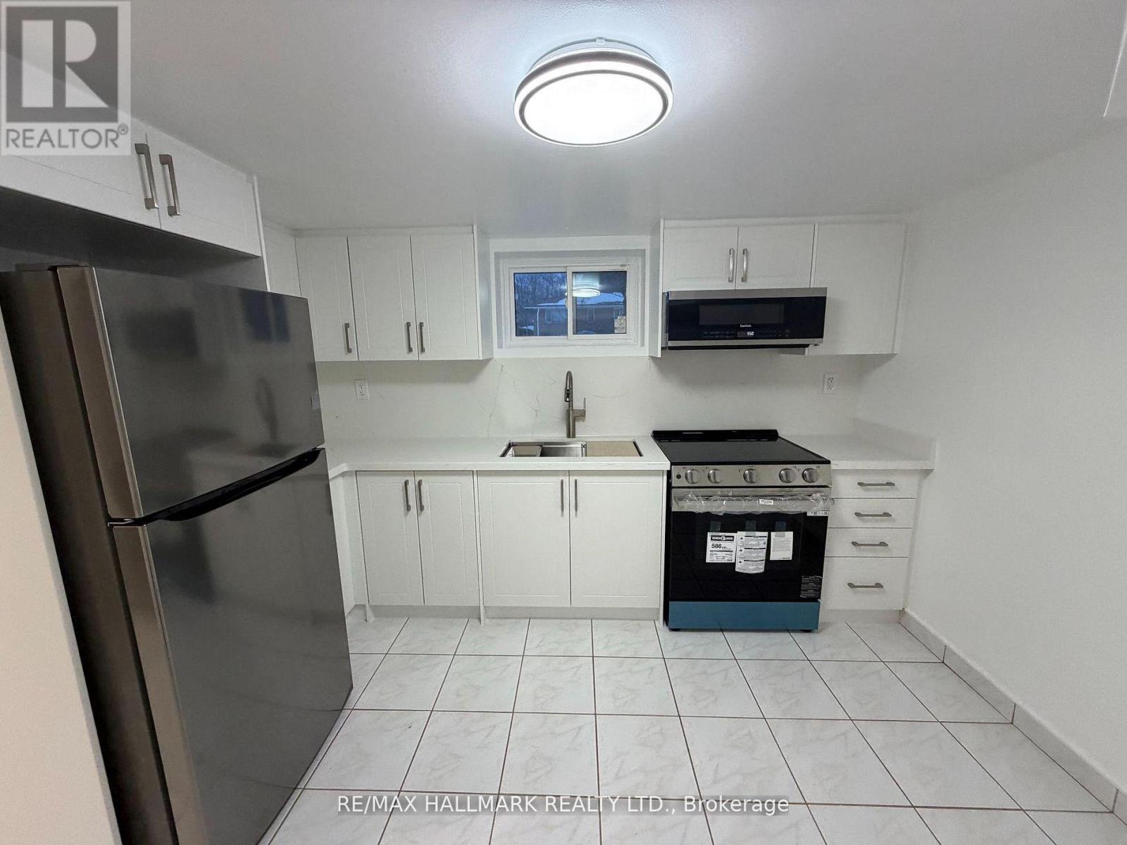 A kitchen with white cabinets and a stainless steel refrigerator.