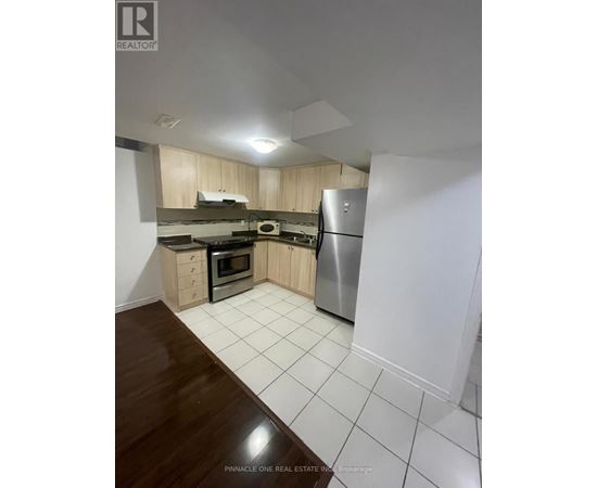 A kitchen with a refrigerator, oven, and microwave.