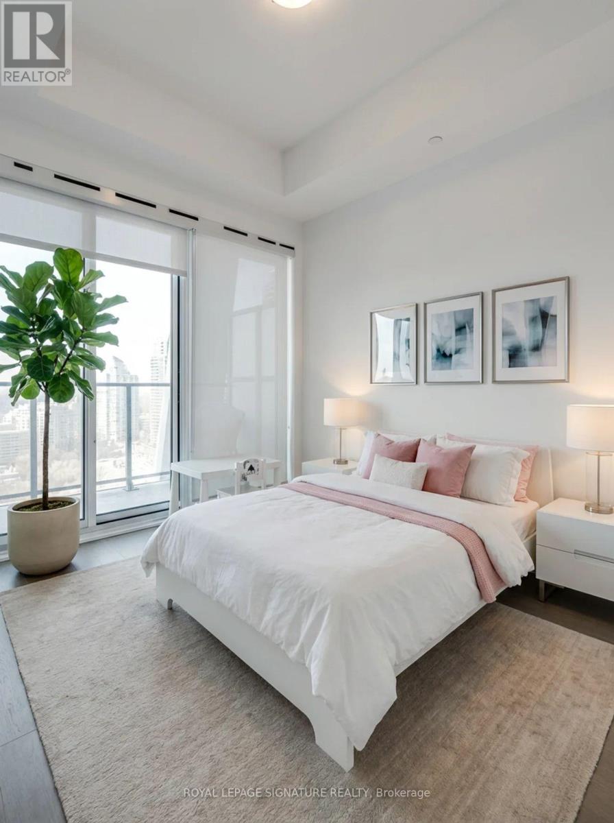 A bedroom with a large bed, a potted plant, and a window.