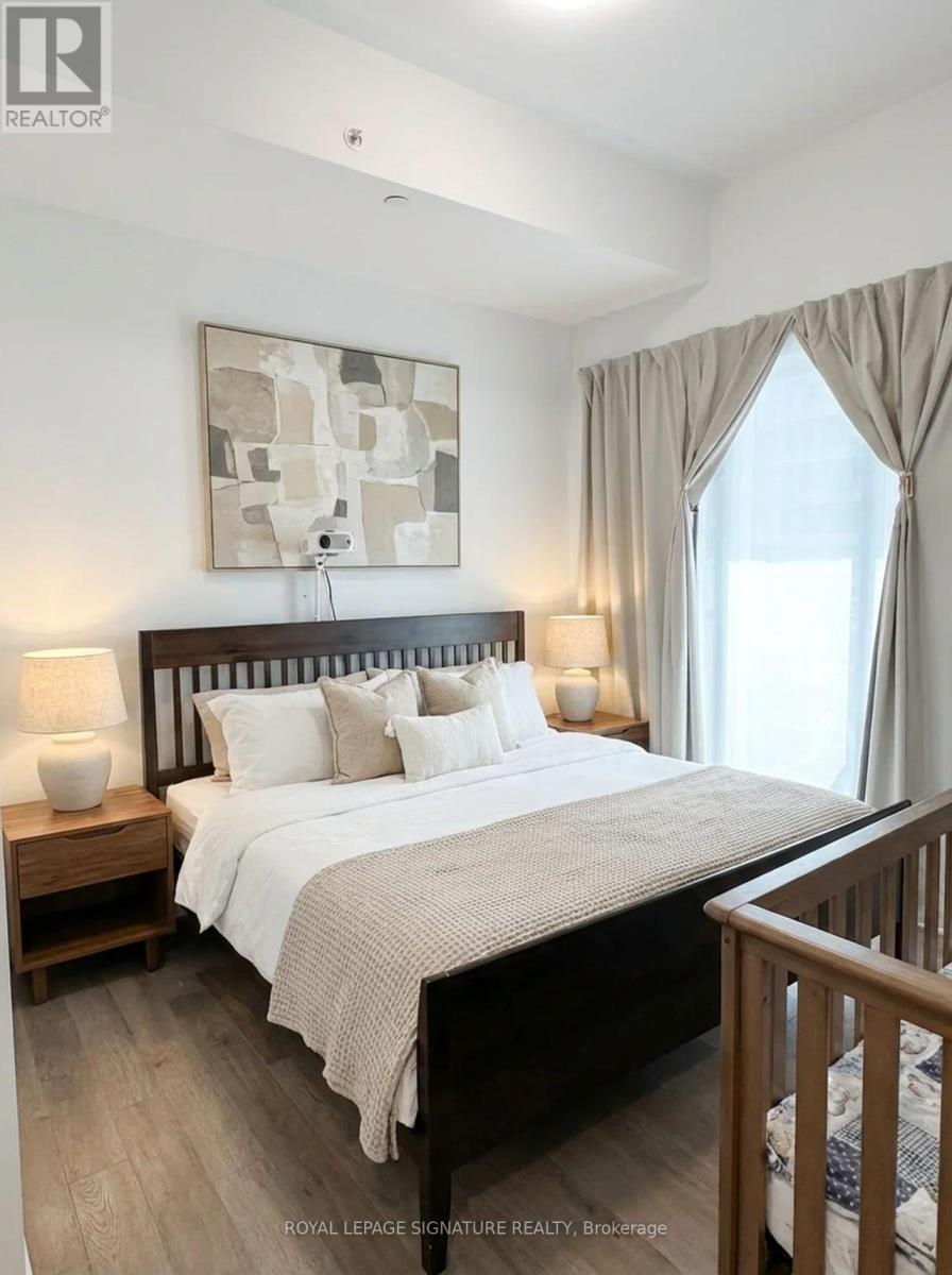 A bedroom with a large bed, a nightstand with a lamp, and a painting on the wall.