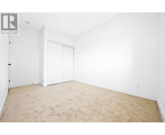 A white bedroom with a carpet floor and a white door.