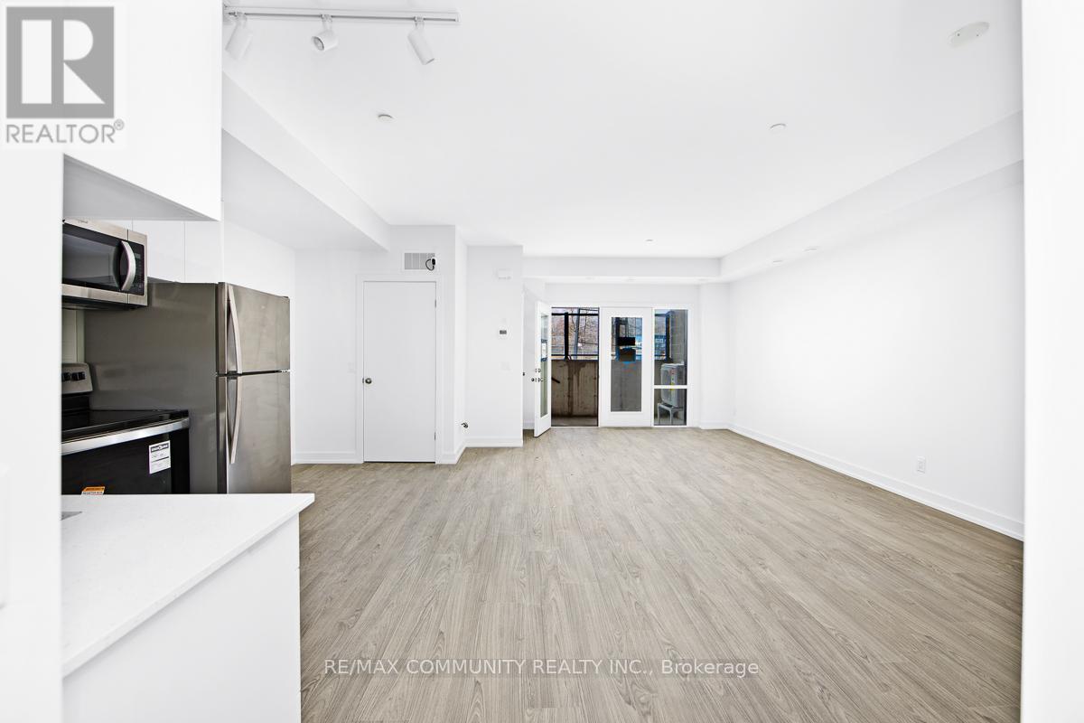 A spacious, empty room with a refrigerator and a white countertop.