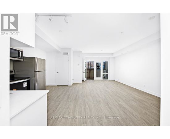 A spacious, empty room with a refrigerator and a white countertop.