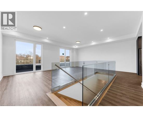 A spacious room with a glass railing and wooden flooring.