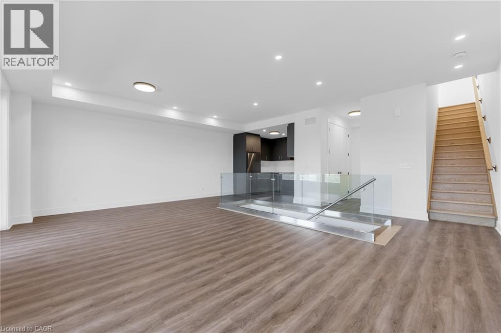 A spacious room with wooden flooring and a staircase.