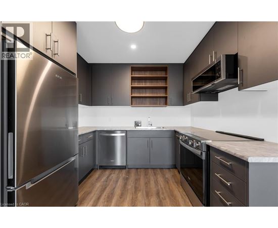 A modern kitchen with stainless steel appliances and wooden floors.