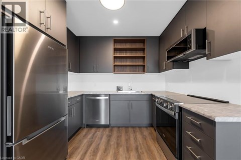 A modern kitchen with stainless steel appliances and wooden floors.