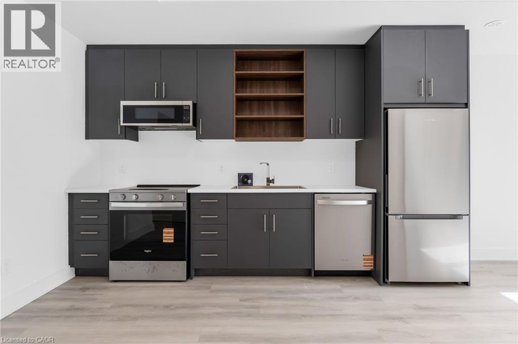A modern kitchen with dark grey cabinets and stainless steel appliances.