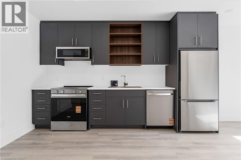 A modern kitchen with dark grey cabinets and stainless steel appliances.