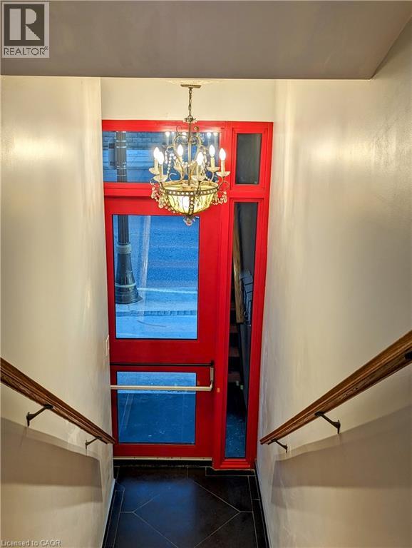 A chandelier hangs over a red door in a hallway.