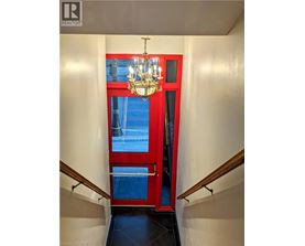 A chandelier hangs over a red door in a hallway.
