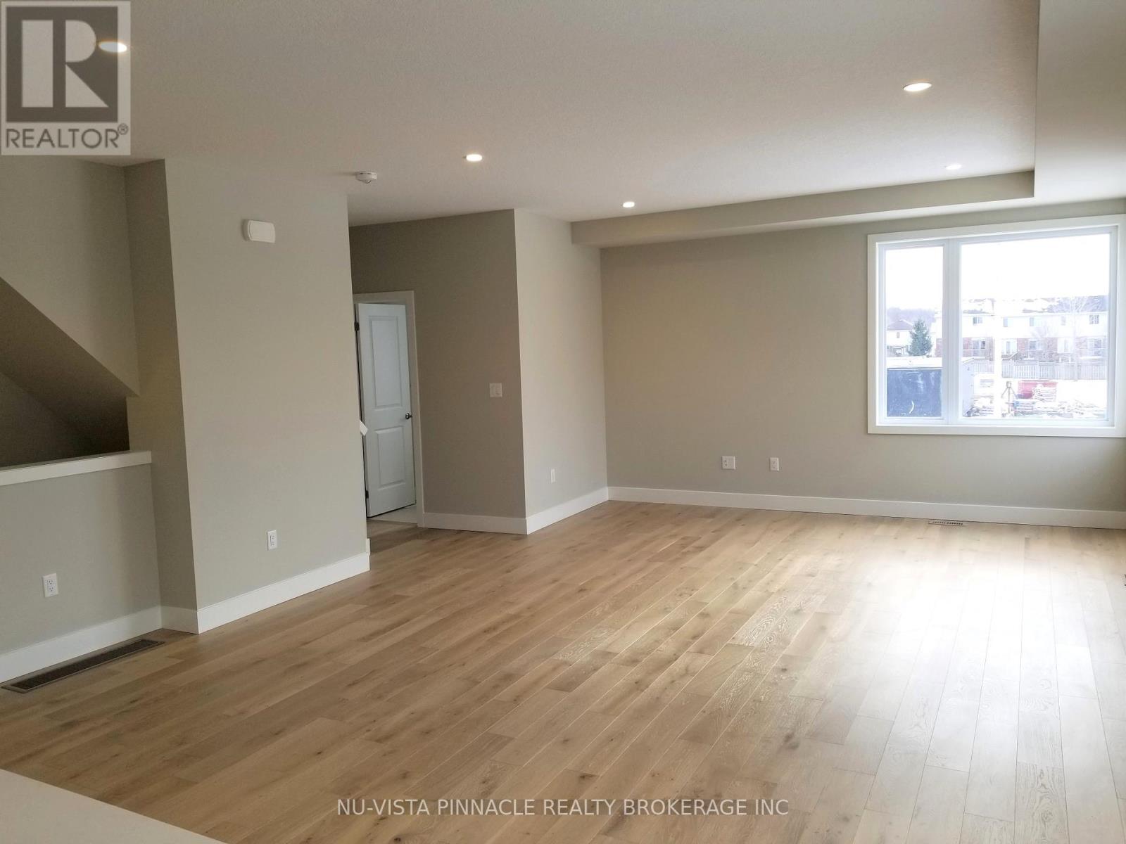 A spacious room with wooden flooring and a large window.