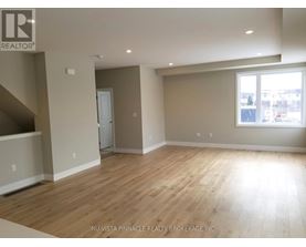 A spacious room with wooden flooring and a large window.
