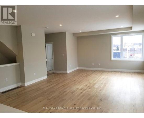 A spacious room with wooden flooring and a large window.