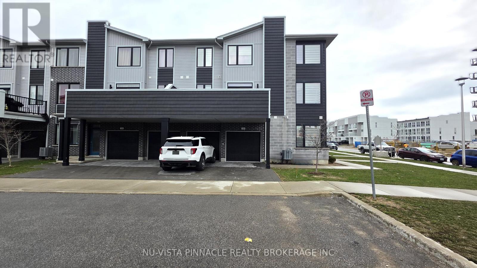 A white car is parked in front of a grey building.