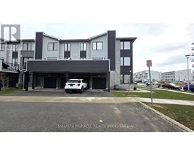 A white car is parked in front of a grey building.