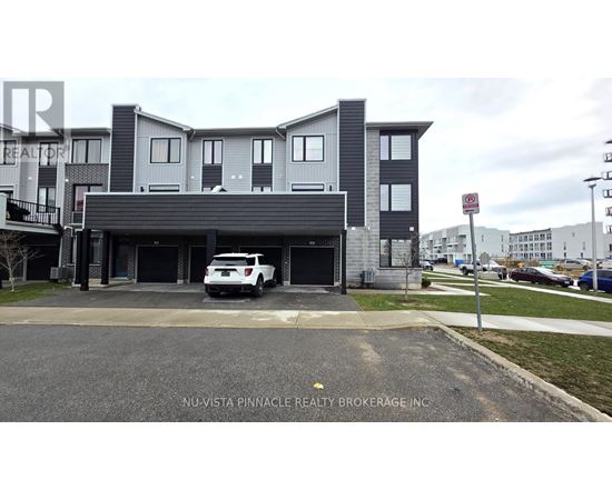 A white car is parked in front of a grey building.