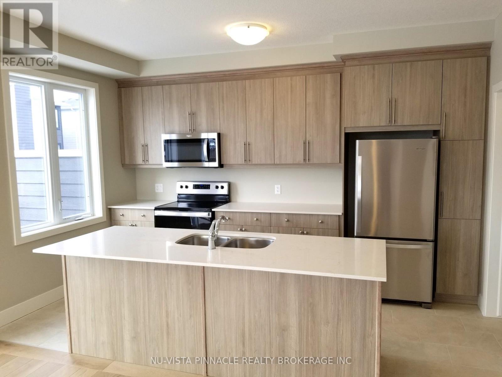 A kitchen with a stainless steel refrigerator and wooden cabinets.