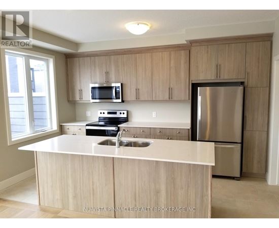 A kitchen with a stainless steel refrigerator and wooden cabinets.
