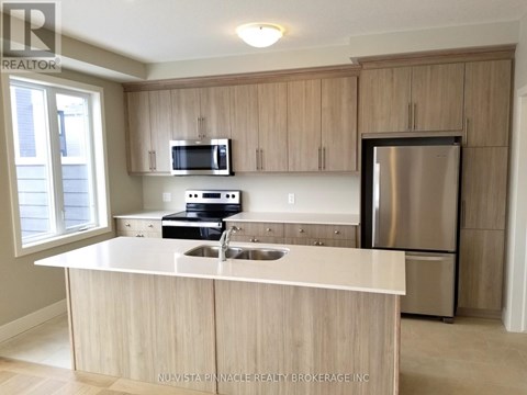 A kitchen with a stainless steel refrigerator and wooden cabinets.