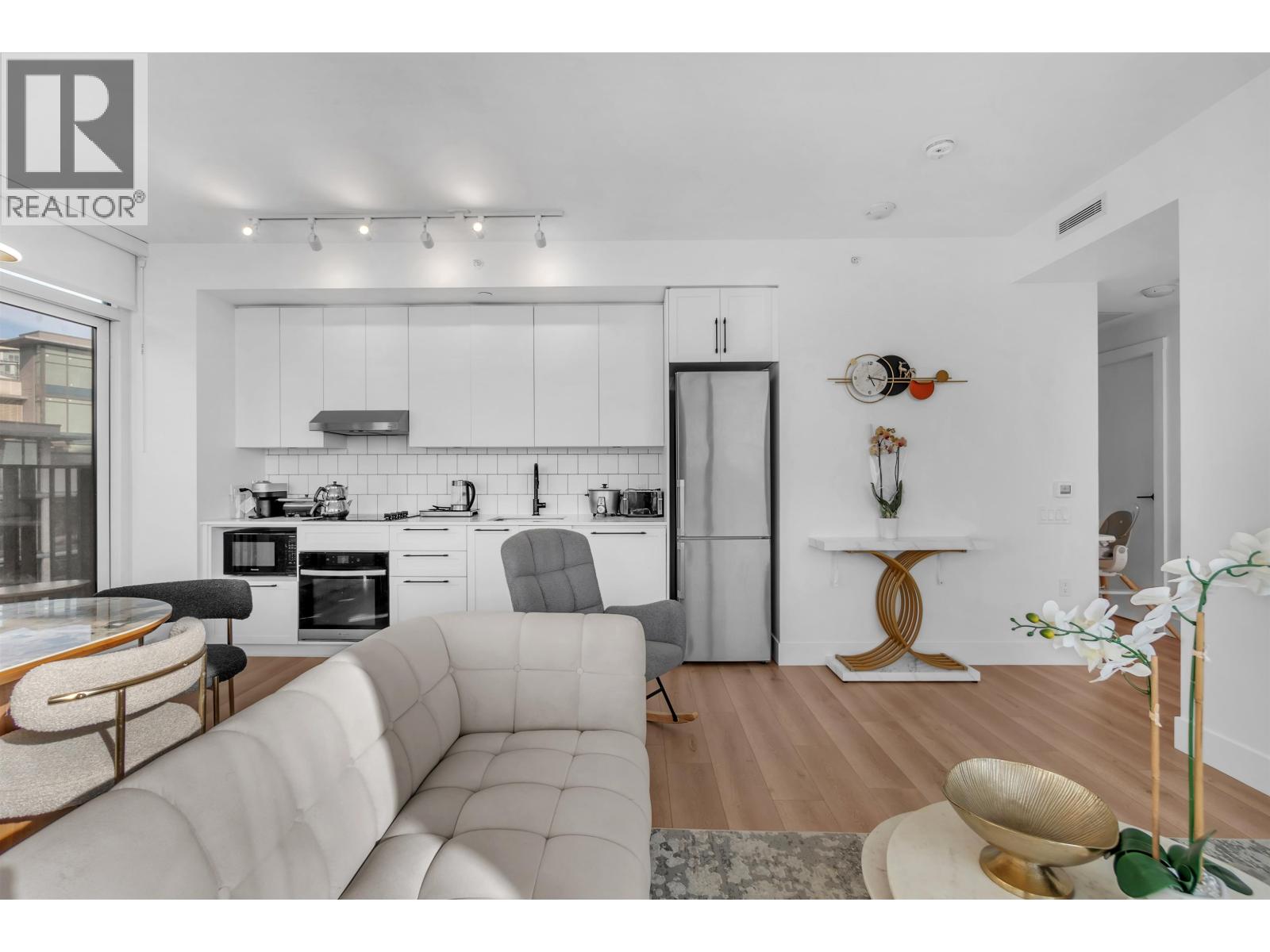 A modern kitchen with a white color scheme and a dining area with a round table and chairs.