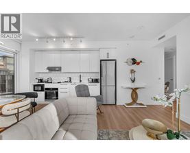 A modern kitchen with a white color scheme and a dining area with a round table and chairs.