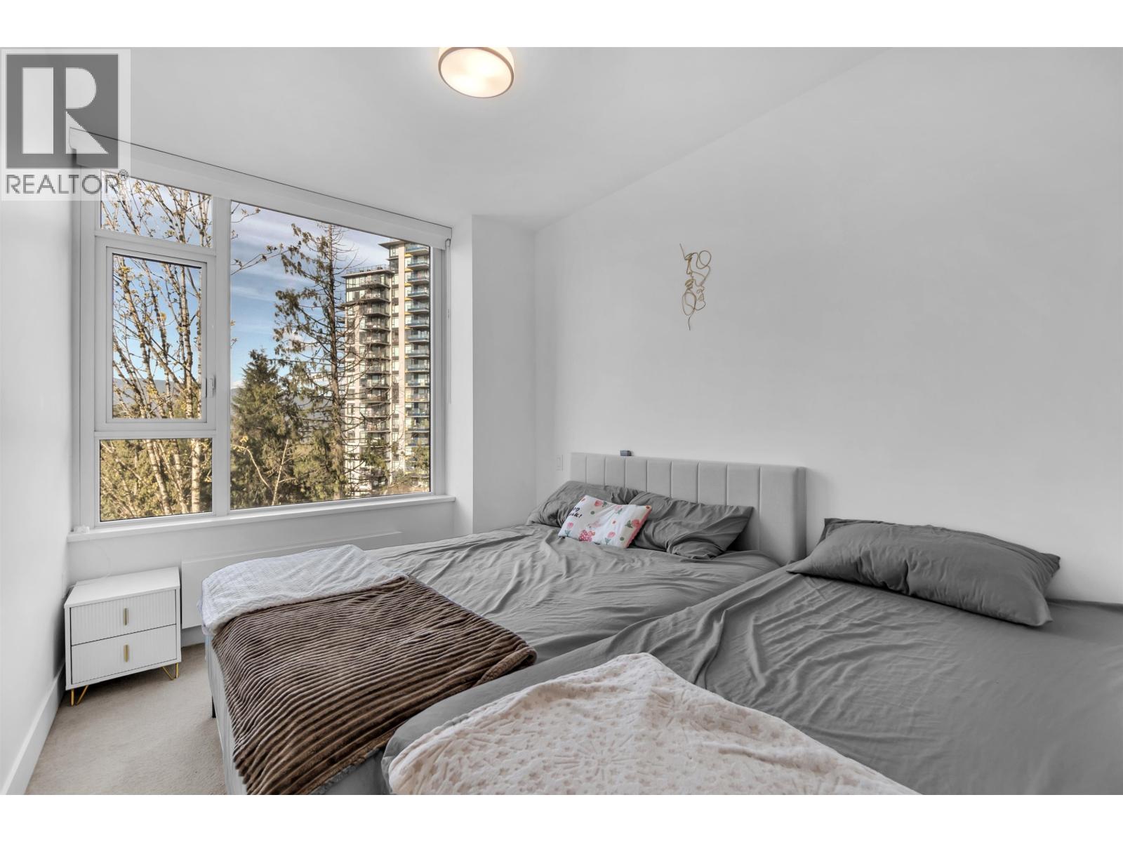 A bedroom with a large bed and a window overlooking a cityscape.
